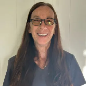 smiling woman with a grey merry maids uniform standing in front of a tan wall